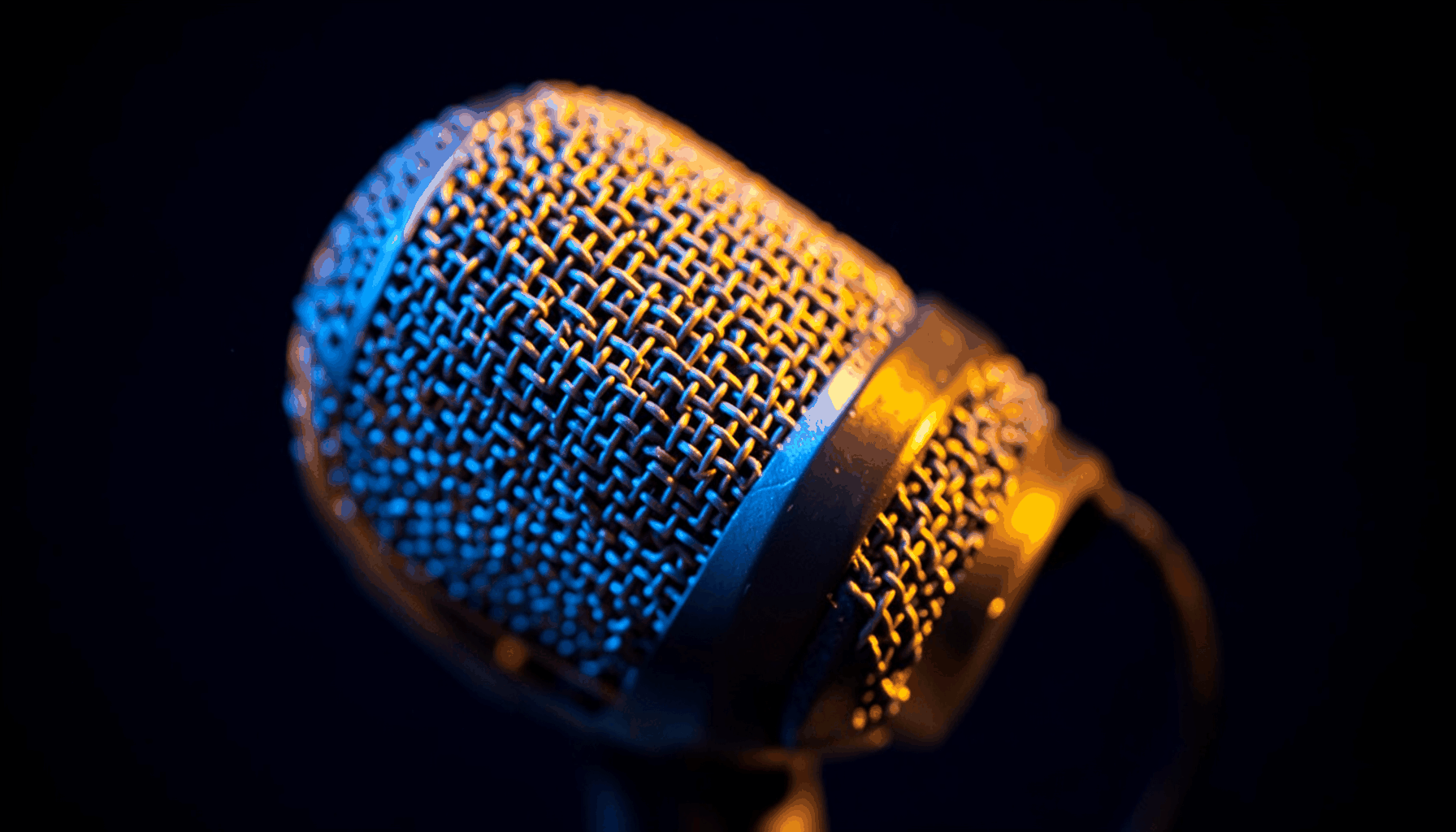 Radio studio microphone with warm amber glow against dark navy background