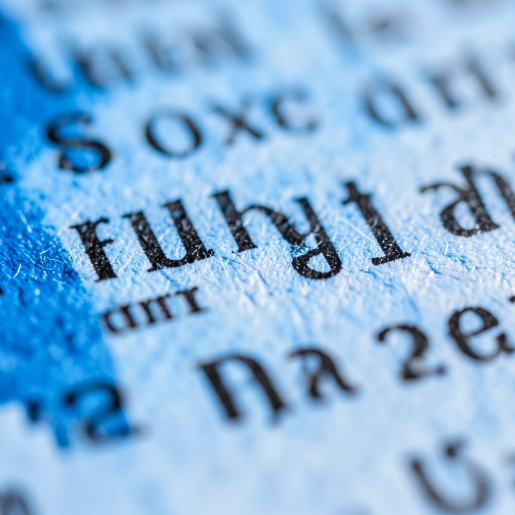 Close-up of textured newsprint paper with black ink lettering under soft diffused light